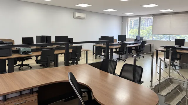 Salão de trabalho visto do alto da escada, com guarda-corpo de vidro e inox